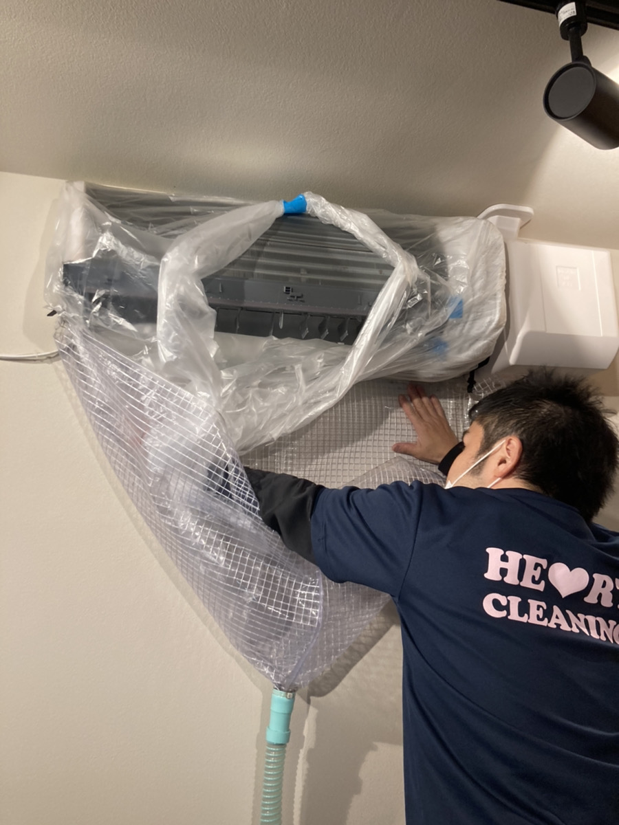 エアコン本体を洗浄シートとビニールで養生する作業
