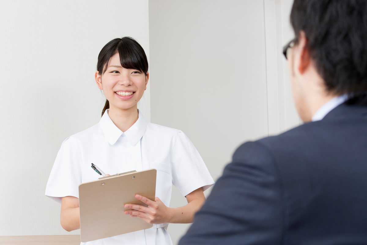 エアコンクリーニングの受付でスタッフが製造年を確認しながら説明している様子
