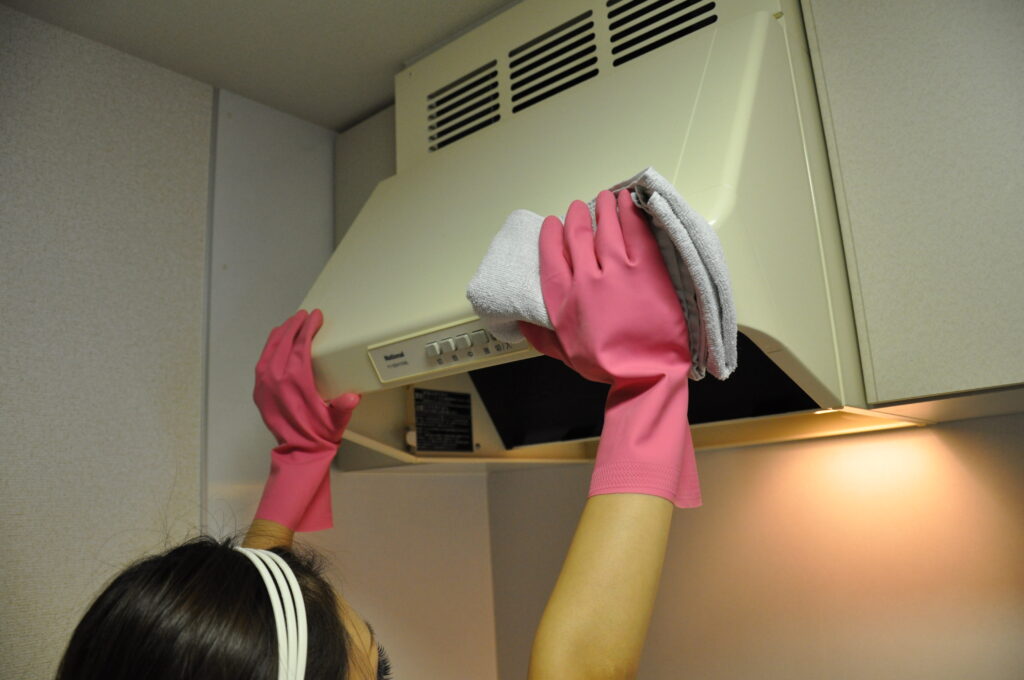 クロスでレンジフードの外側を拭き上げている作業